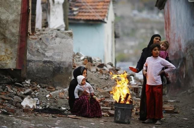 Syrian refugees warm themselves around a fire in Hacibayram district of Ankara