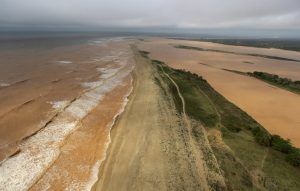 A general view the sea (L) and  Rio Doce (Doce River), which was flooded with mud after a dam owned by Vale SA and BHP Billiton Ltd burst, as the river joins the sea on the coast of Espirito Santo in Povoacao Village, Brazil, November 22, 2015. REUTERS/Ricardo Moraes - RTX1VA3G