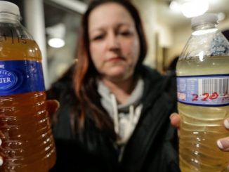 a woman holds lead tainted water in Flint, Michigan
