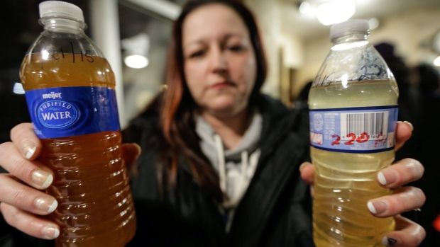 a woman holds lead tainted water in Flint, Michigan