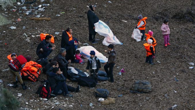 Migrants wearing life jackets wait for a dinghy to sail off for the Greek island of Lesbos from the Turkish coastal town of Dikili
