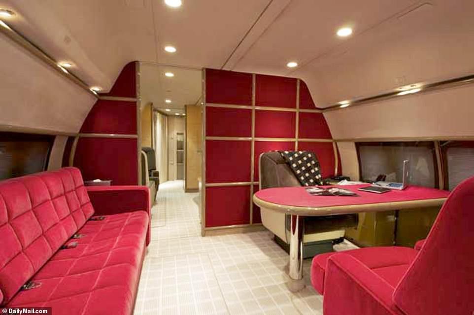 In one room that looks like an office, an Apple laptop computer and Apple iPad sit on the desk and the room has a red velvet chairs and a sofa