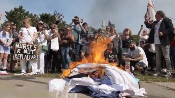 Fired New York healthcare workers burn their scrubs in protest to vaccine mandates