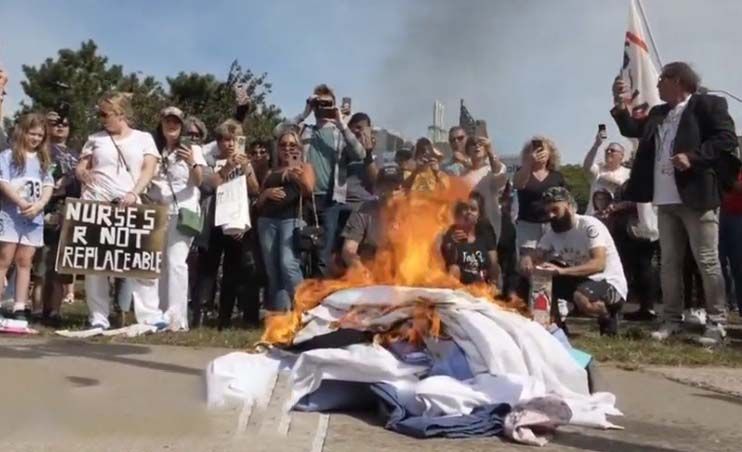 Fired New York healthcare workers burn their scrubs in protest to vaccine mandates